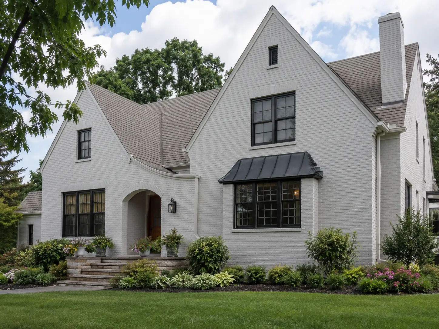 Freshly painted white brick home with dark trim, landscaped front yard, and mature trees on the South Shore.
